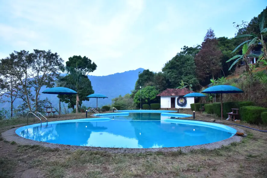 The pool with umbrellas, forest and hills around it